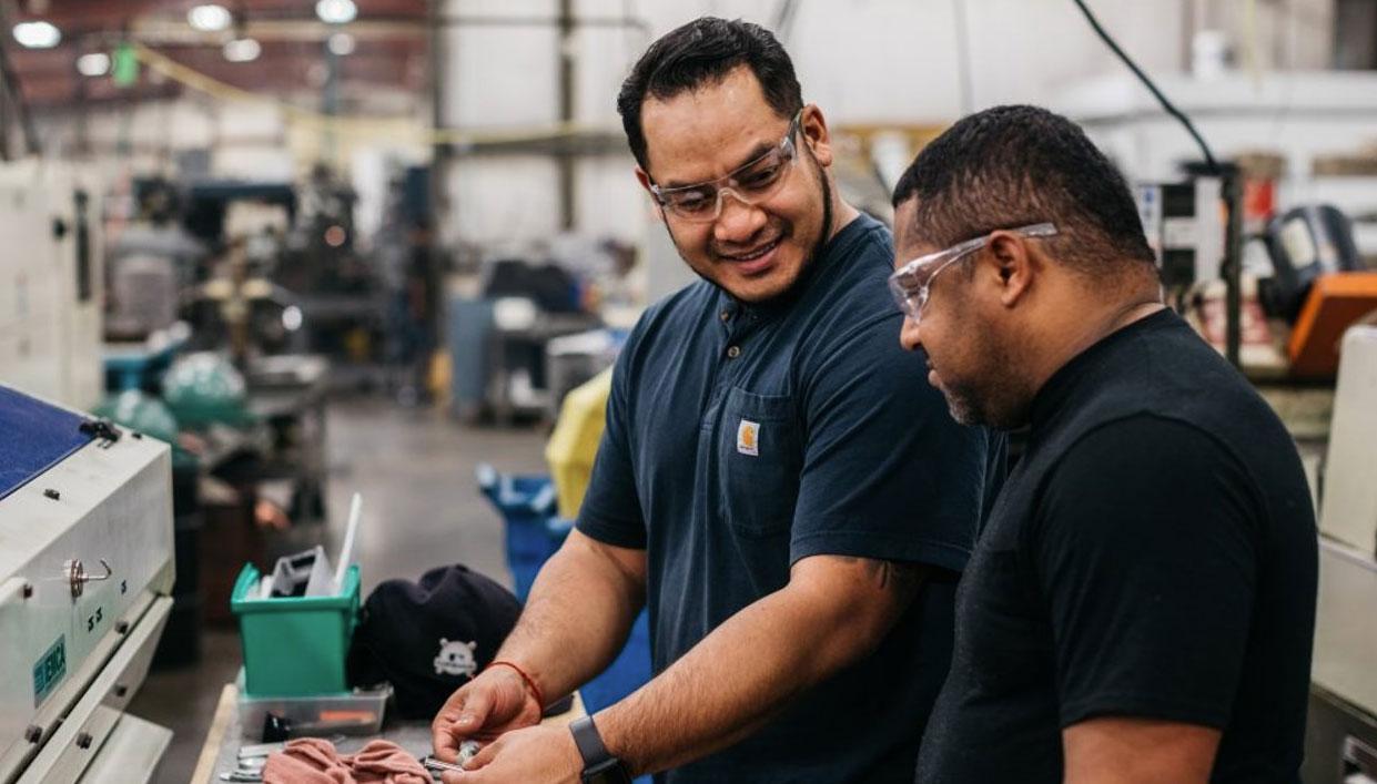 trainee-employees-in-manufacturing-environment two manufacturing trainees talking in a manufacturing workshop